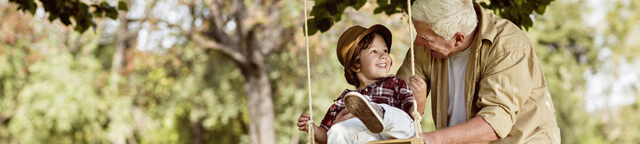 Grandfather pushes grandchil on a swing